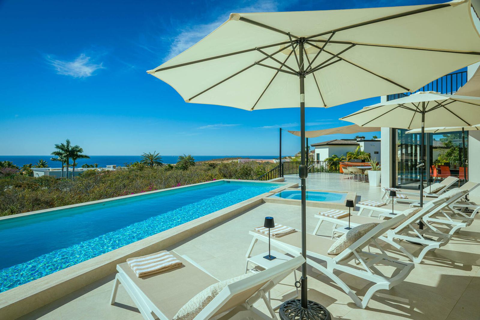 Long infinity pool with white loungers and umbrellas at Casa Alba in Puerto Los Cabos