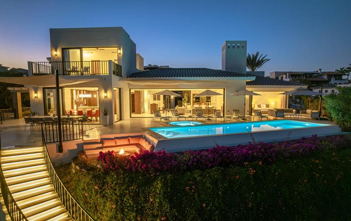Casa Alba at dusk, its contemporary white facade and illuminated pool above a stepped garden