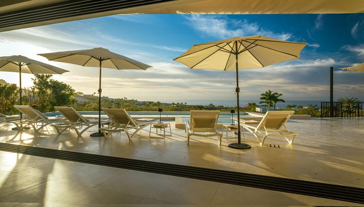 Shaded terrace with loungers and umbrellas overlooking the pool and ocean at Casa Alba