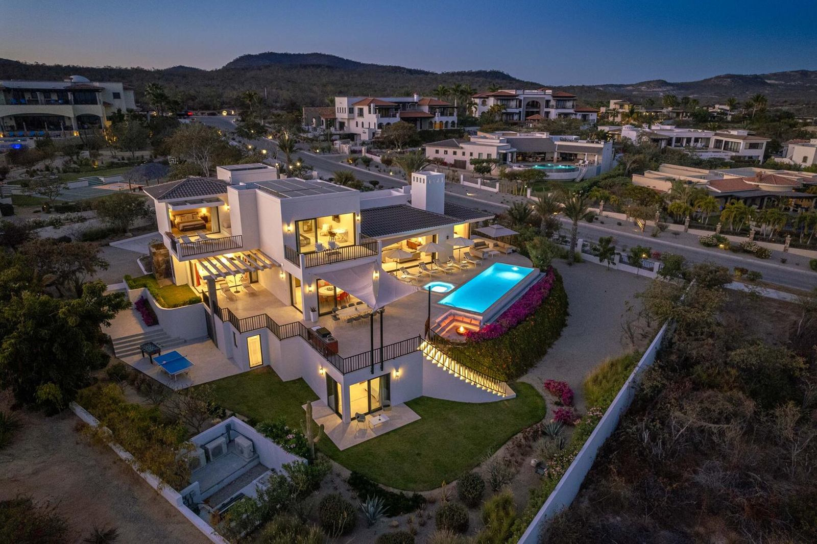 Aerial view of a contemporary villa on a hillside in Puerto Los Cabos at dusk