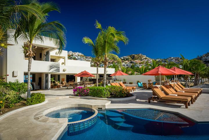 Pool terrace at Casa Alcini with palm trees, loungers and the villa's white facade