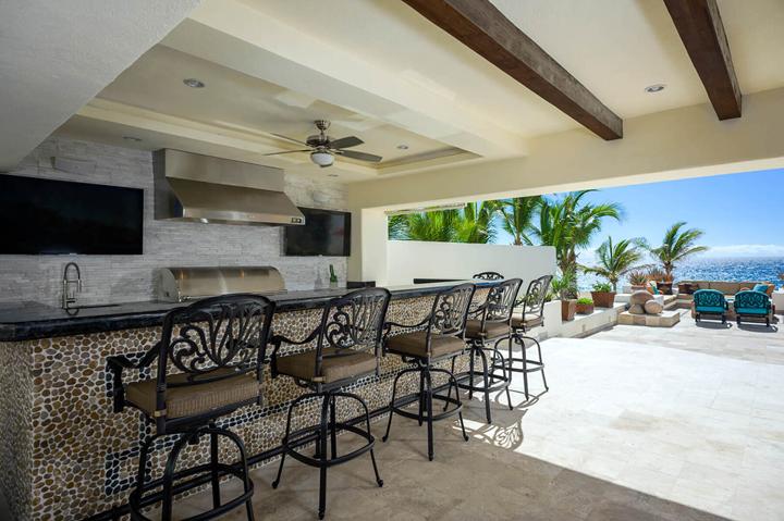Outdoor bar with seating for a group beneath the covered terrace at Casa Alcini