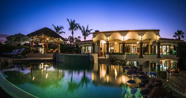 Casa Alegria at twilight, with its lit arches reflected in the pool