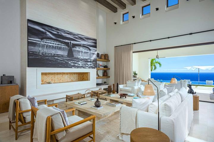 Living room with fireplace and a wall of glass framing the ocean at Casa Catrina