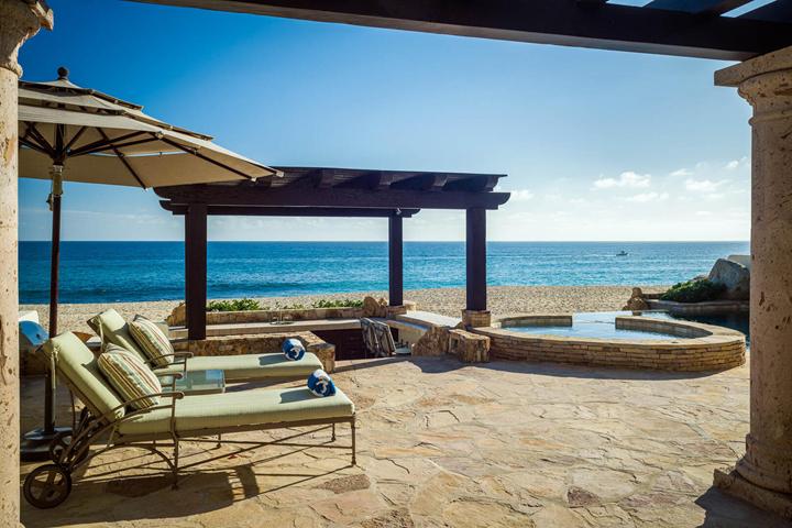 Cushioned loungers under a shade umbrella beside the Jacuzzi at Casa Cielo