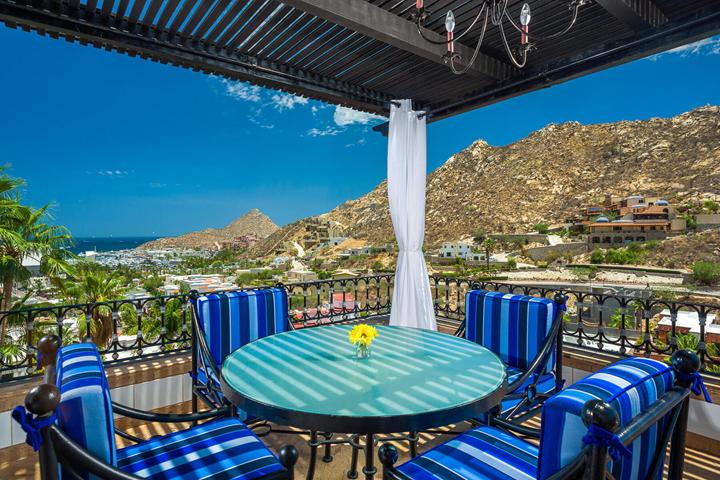 Terrace dining table with blue striped chairs and hillside views at Casa Connie