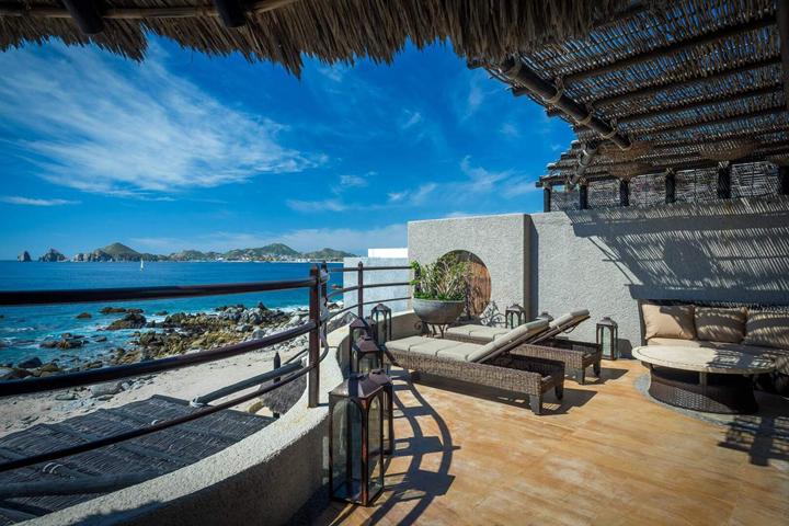 Covered terrace with day beds and ocean views at Casa del Arco