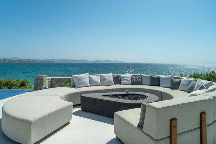 Curved outdoor sofa around a fire pit overlooking the ocean at Casa Elije