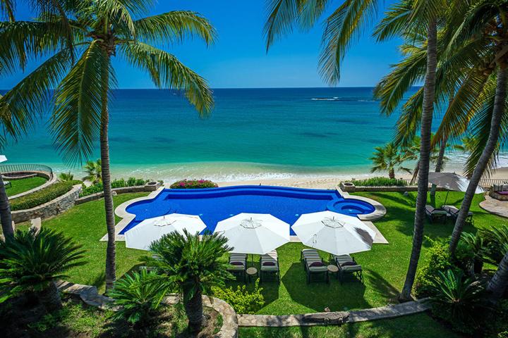 Aerial view of a beachfront pool, umbrellas and palms in Palmilla