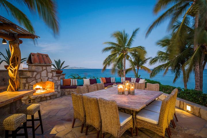 Outdoor dining by a stone fireplace at dusk at Casa Koll Estate