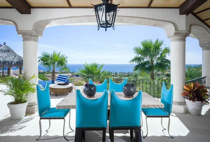 Covered dining terrace with turquoise chairs and ocean views at Villa Buena Vida